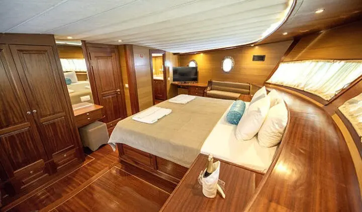 Master cabin on Kayhan 4 yacht with king bed, wood floors, bedside lamps