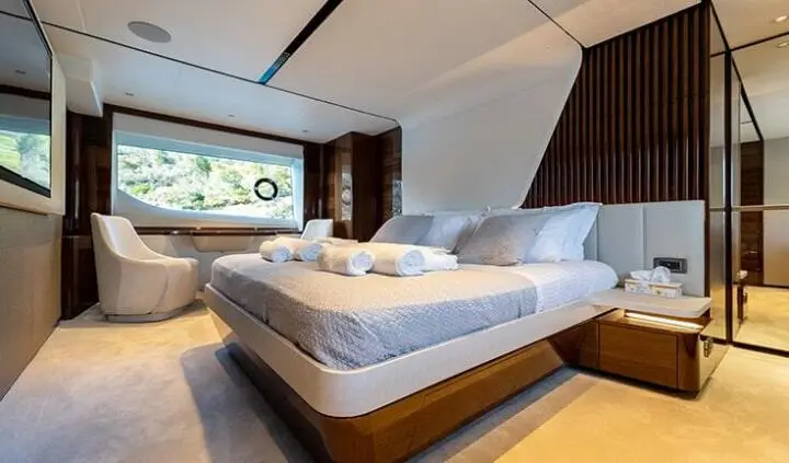 Vista yacht cabin with king bed, white bedding, wooden floor, and window view