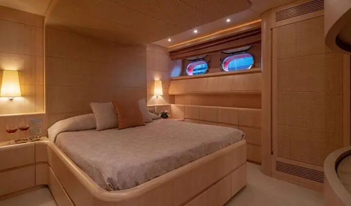 Glaros cabin bedroom with king bed, wooden walls, padded headboard, soft lighting