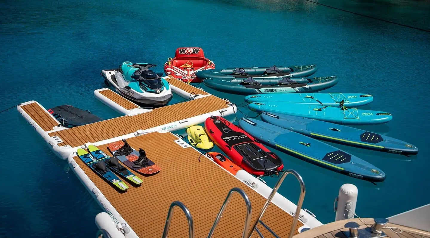 Luxury motor yacht Anima Maris docked at a pier with colorful boats nearby