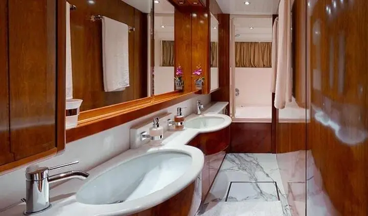 Lady Natassa cabin interior with twin marble sinks, wood paneling, and mirrored vanity