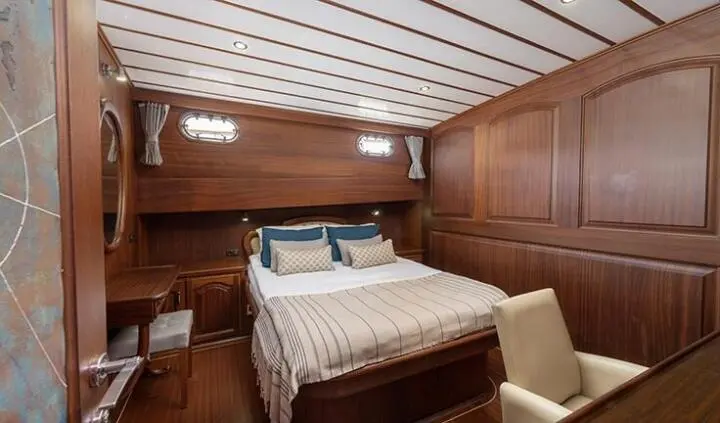 Master cabin with king bed, wood paneling, bedside lamps, and ensuite-like doorway