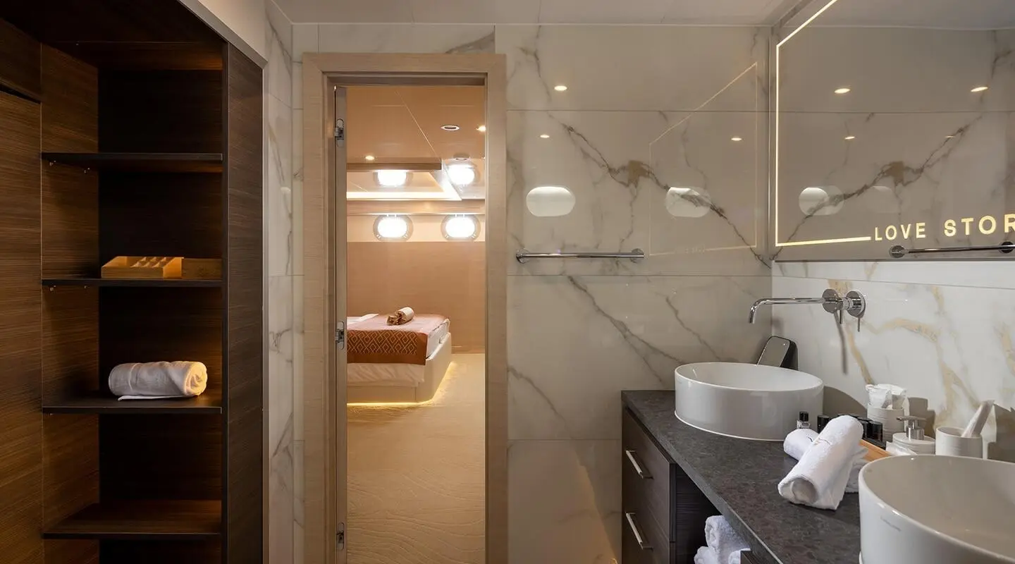 Love Story luxury yacht interior: polished wood, bed, and bathroom, warm lighting