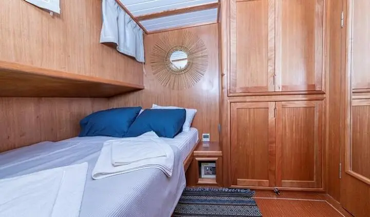 Master cabin with king bed, blue throw pillows, wood paneled walls, ensuite door