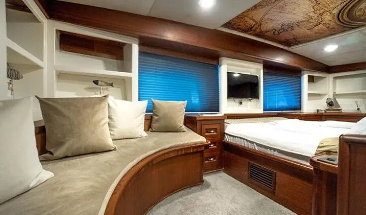 Master cabin on Virtuoso yacht with king bed, beige seating, and wood finishes