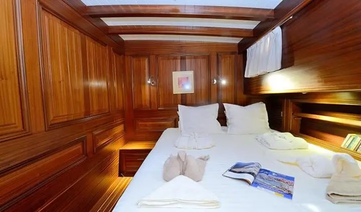 Cozy wooden yacht cabin with two white beds and pillows, warm lighting