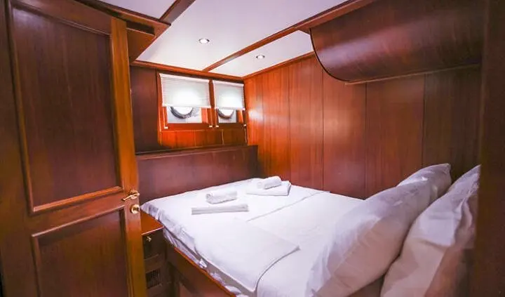 Gazella yacht cabin with two neatly made beds and wood paneling