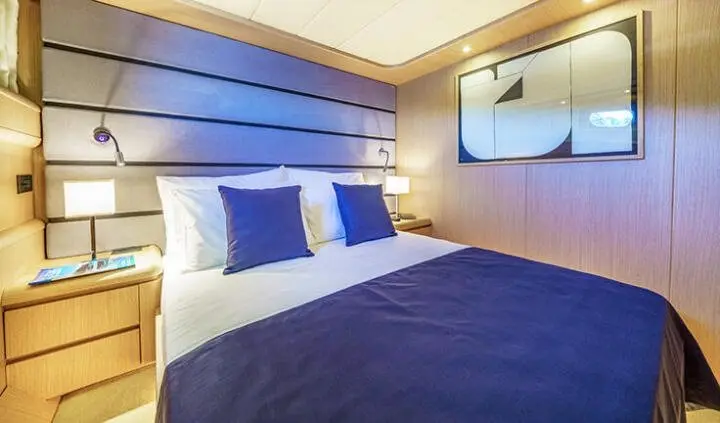 Phantom yacht cabin with king bed, dark blue bedding, and beige walls