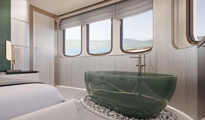Maia yacht cabin with large bed, green upholstered headboard, windowed view, sunlight flooding the space