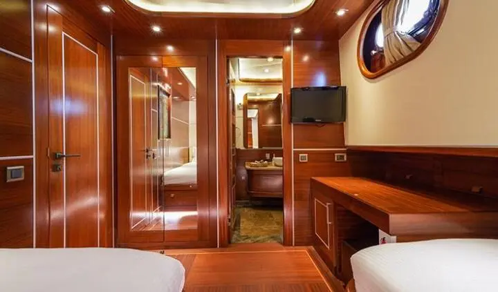 La Bella Vita cabin interior with wooden bed, warm lighting, and compact helm area