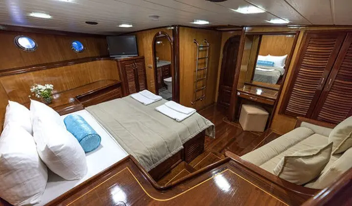 Master cabin with king bed, ensuite, wood paneling, portholes, and seating