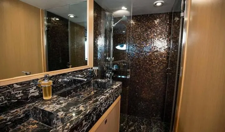 Master cabin with king bed, ensuite, dark marble surfaces and wood fixtures
