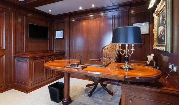 Master cabin with king bed, wooden panels, nightstands, and desk lighting