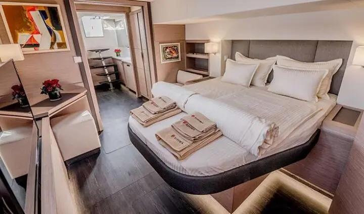 Astoria yacht cabin with queen bed, beige linens, and wooden accents