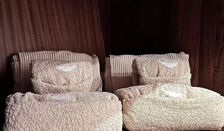 Two beige bedduveted cabins with patterned pillows and dark curtains