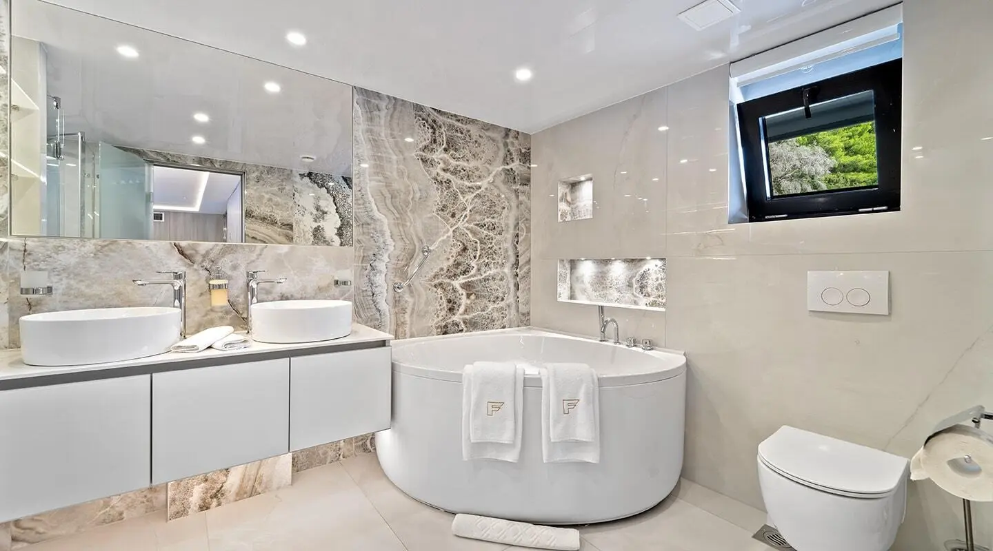 Luxurious bathroom aboard Freedom yacht with stone walls and white tub