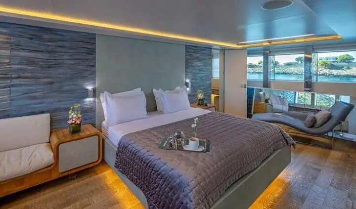 Sea Wolf cabin bed with white linens, purple blanket, and bedside lamps