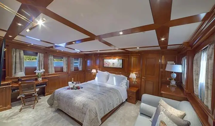 Luxurious yacht master cabin with king bed, wood paneling, and ensuite doorway