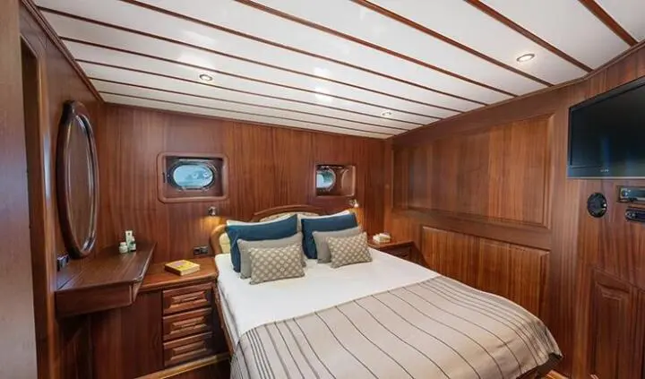 Twin bed cabin with wood paneling, striped bedding, and porthole window
