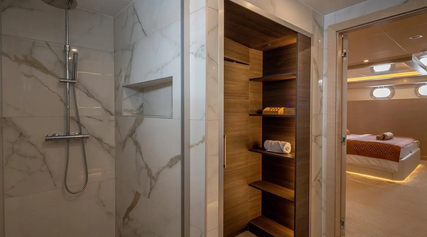 Open wooden built-in closet with shelves and a marble wall behind it on a yacht interior