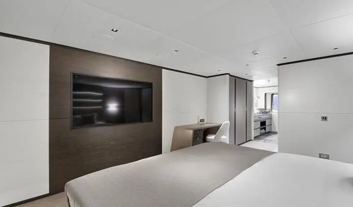 Master cabin with king bed, ensuite, and flat-screen TV on wood panel wall