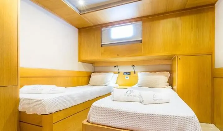 Yacht cabin interior with twin beds, wooden panels, and small window