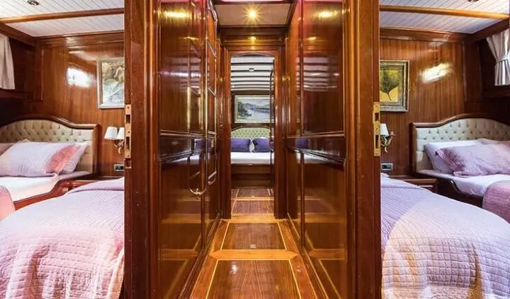 Master cabin with king bed and ensuite doorway framed by wood panels