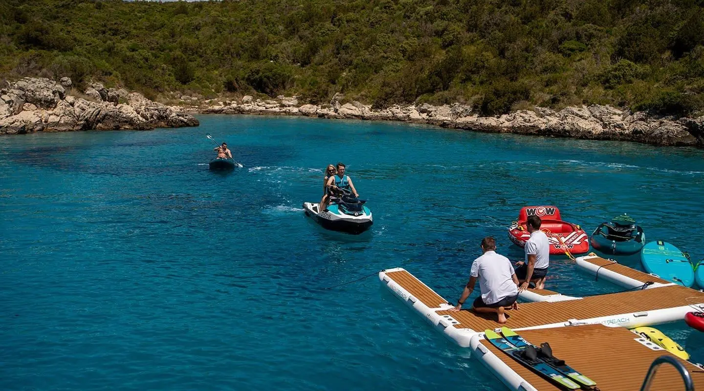 Anima Maris yacht anchored near rocky coastline with people on a small boat