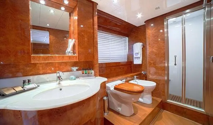 Master cabin with king bed, ensuite bath, wood panels, and porthole window