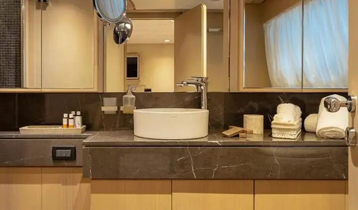 Interior of yacht cabin with wooden cabinets, mirror, and lighting fixtures