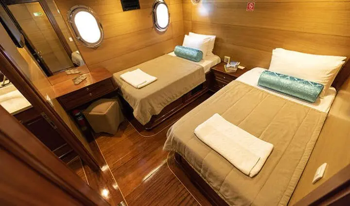 Yacht Kayhan 4 cabin twin bedded stateroom with wooden flooring and porthole lights