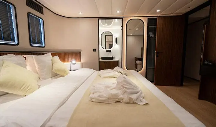 Master cabin with king bed, plush headboard, ensuite door visible