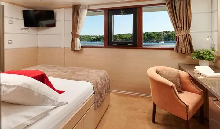 Queen Eleganza yacht cabin with bed, window view, and seating area
