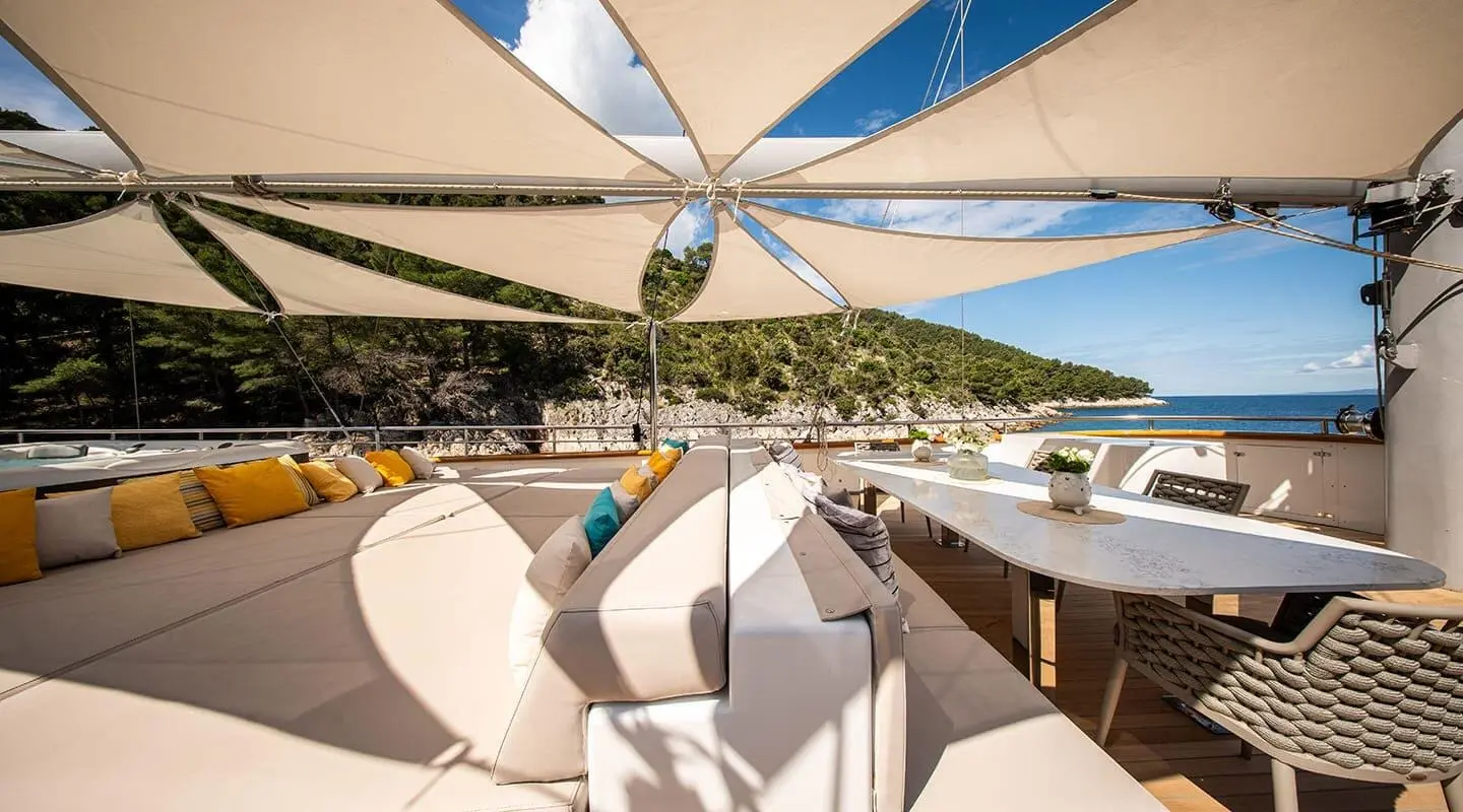 A luxury yacht Dalmatino docked with beige seating and shade sails overhead
