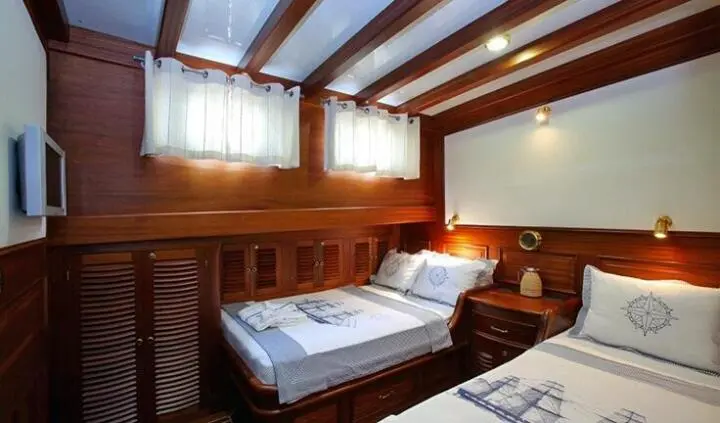 Twin cabin wood interior aboard Kaya Guneri 4 yacht, two single beds and porthole light