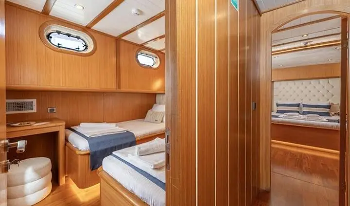 Twin wooden berths in a small yacht cabin with porthole and wood paneling