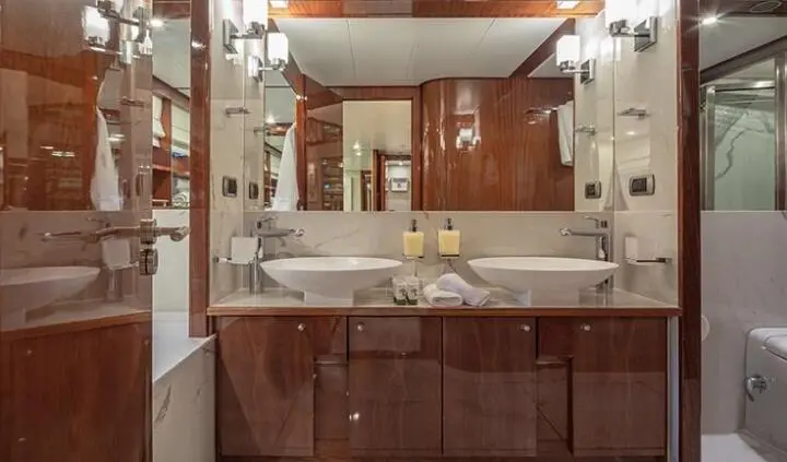 Grace yacht cabin bed with white linens, wood cabinetry, and ensuite reflection