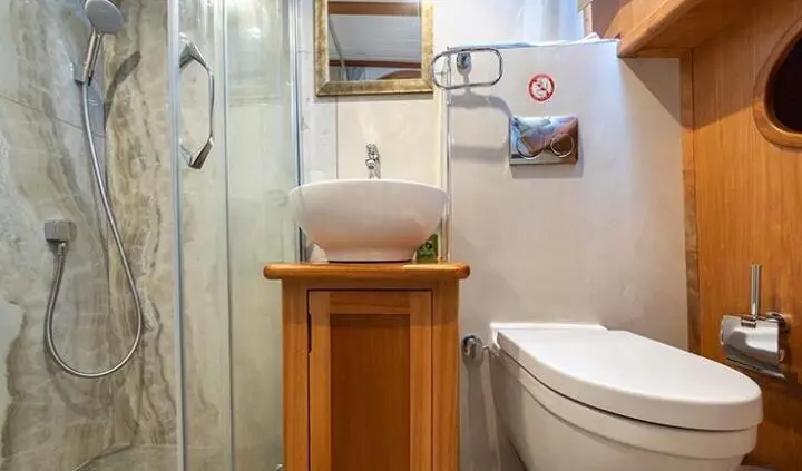 Small wooden cabinet with sink and mirror in a compact yacht cabin bathroom