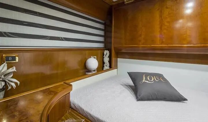 Yacht Amoraki master cabin with large bed, wooden panels, and bedside lamps