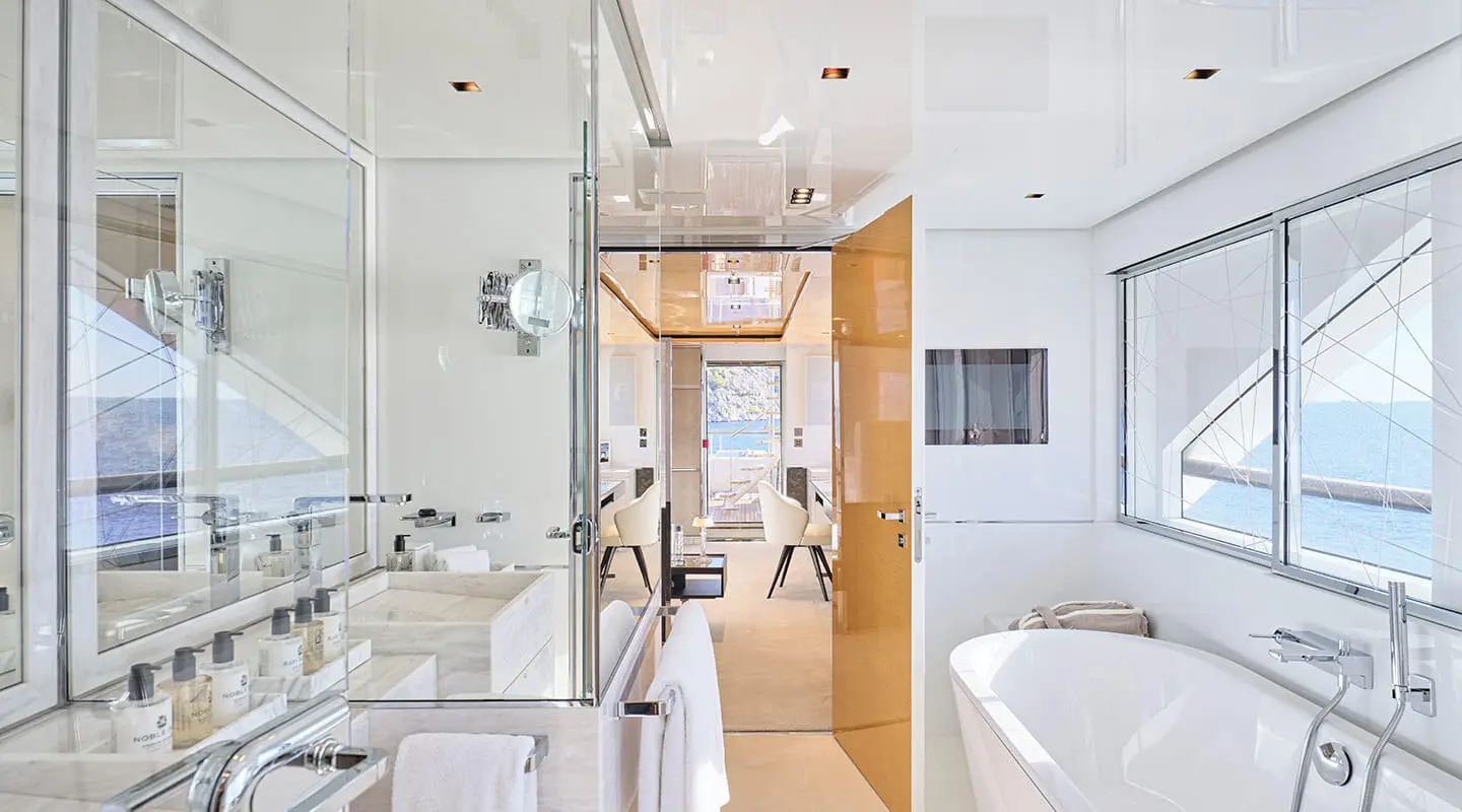 Interior of a luxurious yacht with sunlit white cabin, wooden doorway, and modern fixtures