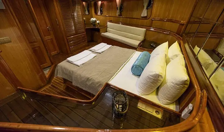 master cabin with king bed, wood paneling, bedside lamps, and white linens