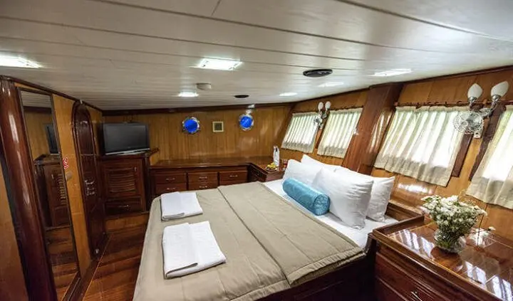 Master cabin with king bed, white bedding, wood-paneled walls, blue cushions