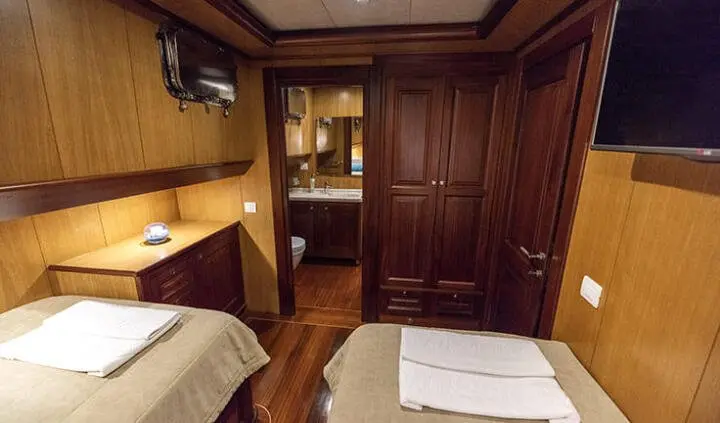 Cabin interior on Kayhan 3 yacht with wood panels, beds, and built-in wardrobe