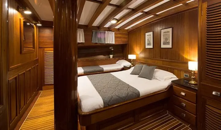 Master cabin with king bed, white linens, wood paneling, and ensuite hint