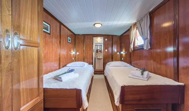 Luna yacht cabin with two single beds, wood-paneled walls and windows