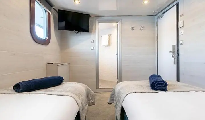Twin cabin interior with two single beds, navy accents, ensuite door