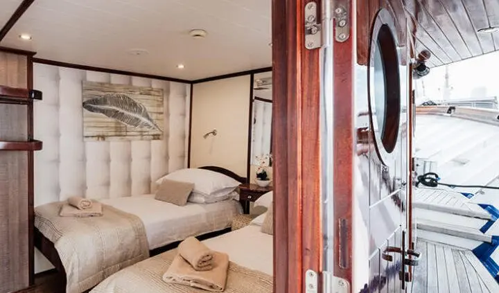Mendula cabin interior with twin beds, soft lighting, and wood-toned walls