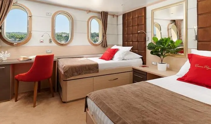 Twin cabin ensuite aboard Queen Eleganza with two single beds and porthole windows