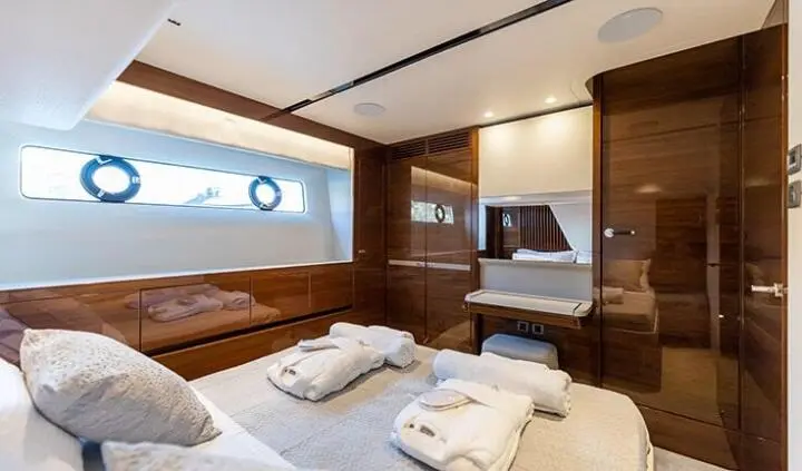 Cozy yacht cabin interior with bed, pillows, wooden cabinets, and window