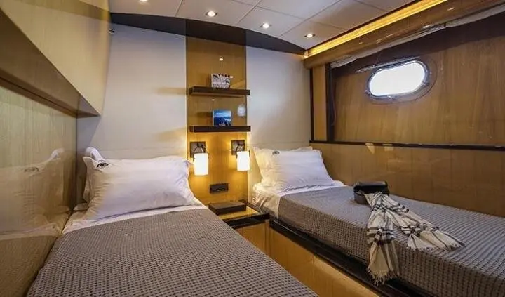 Twin-cabin wood interior of yacht with two single beds and wooden cabinetry